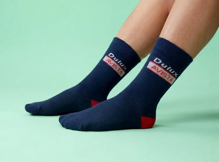 A person wearing navy full terry work socks with Dulux AVISTA logo on sides and with red heel.
