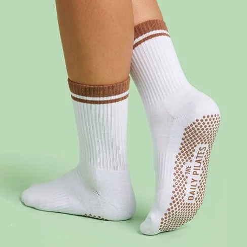 White sports crew socks with custom grip design on sole which says The Daily Pilates