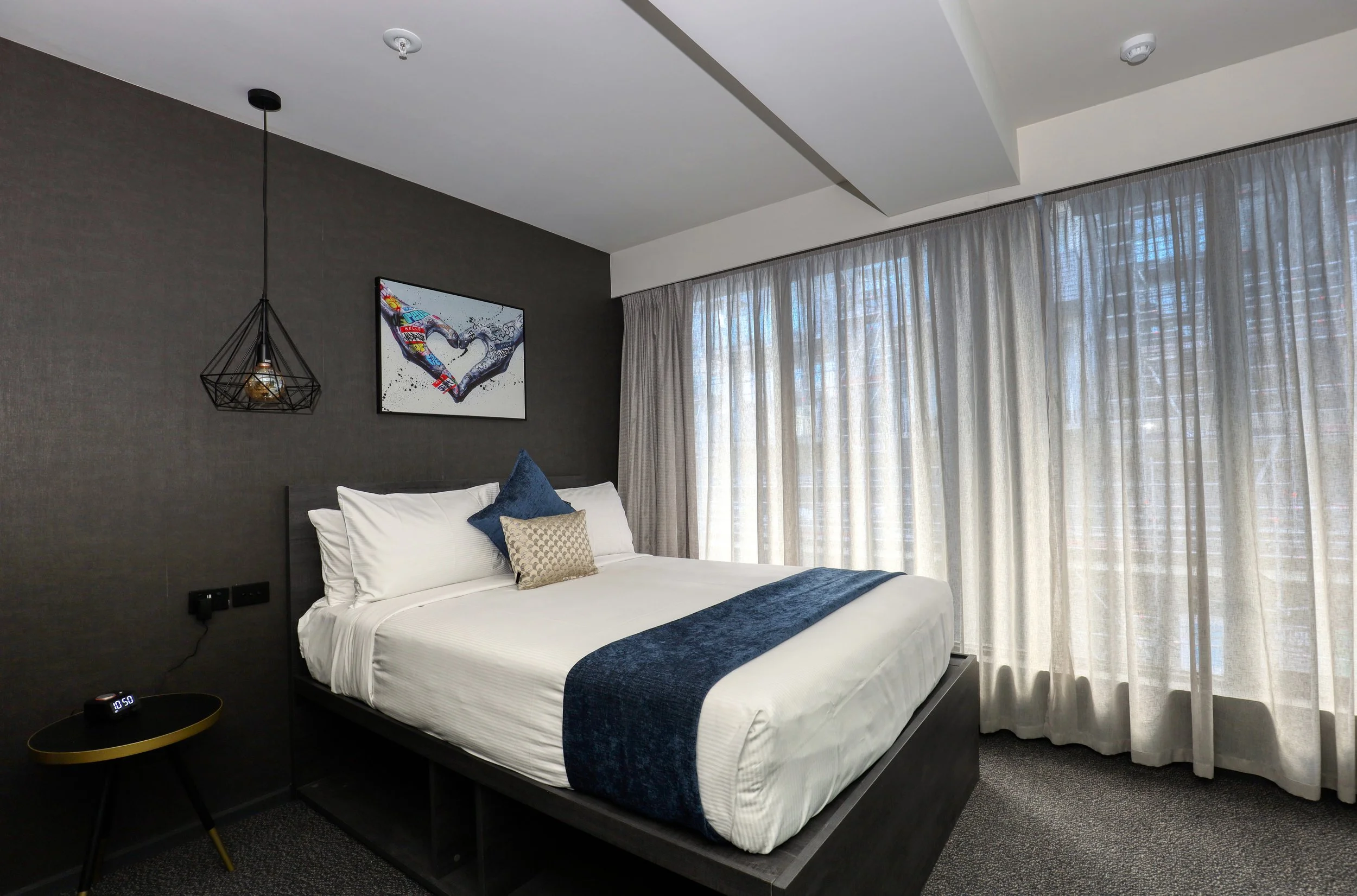 Deluxe Queen room at The Viv Hotel in Wellington featuring a queen bed, floor-to-ceiling windows and contemporary boutique décor.