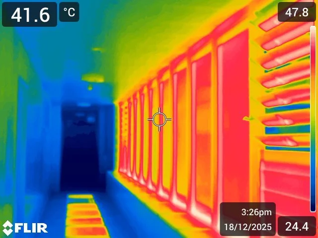 Infrared image of a hallway with heated storage units or lockers, showing varying heat levels indicated by colors from blue to red.