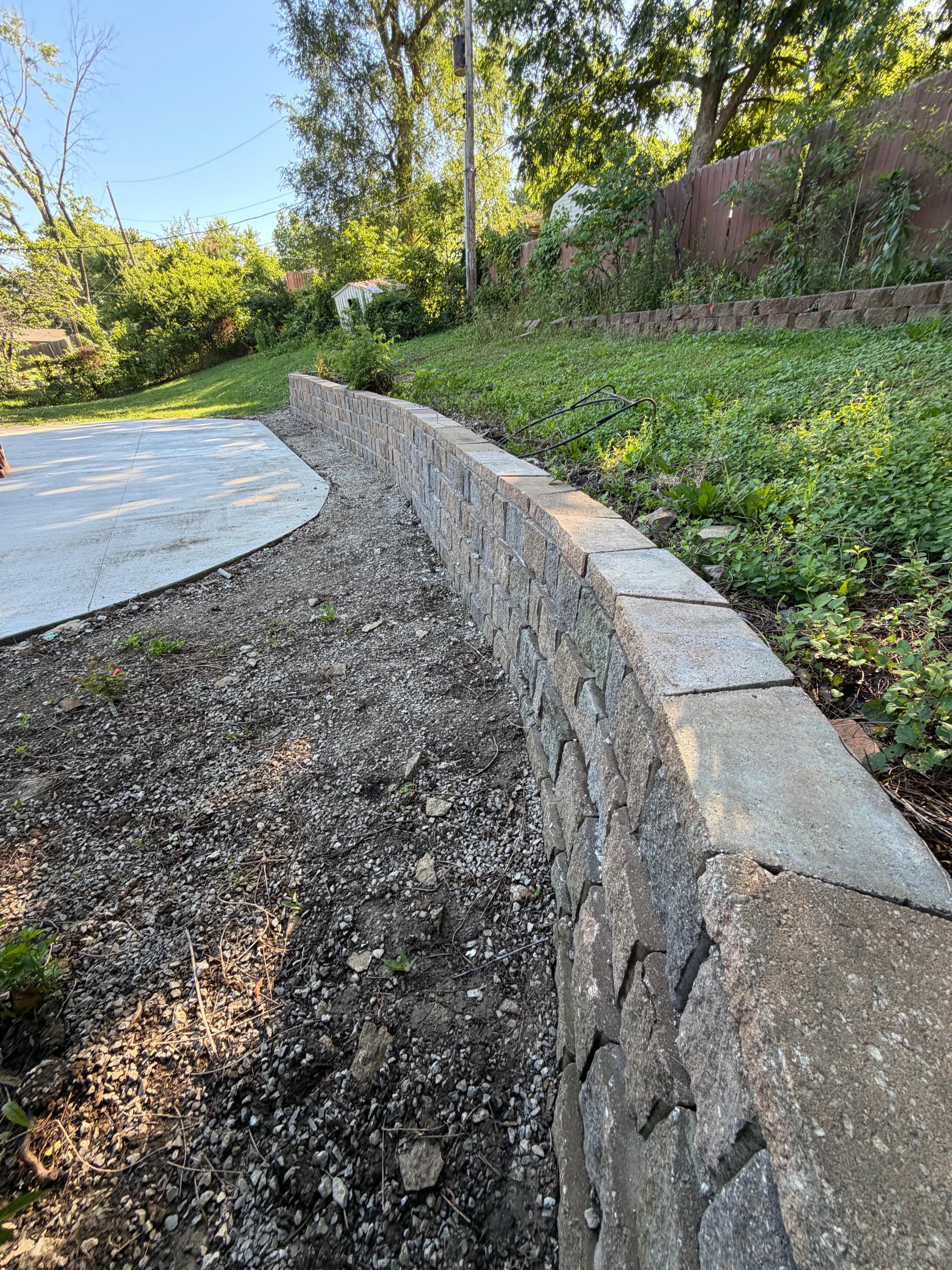 Finished — the capped wall and oval patio at golden hour