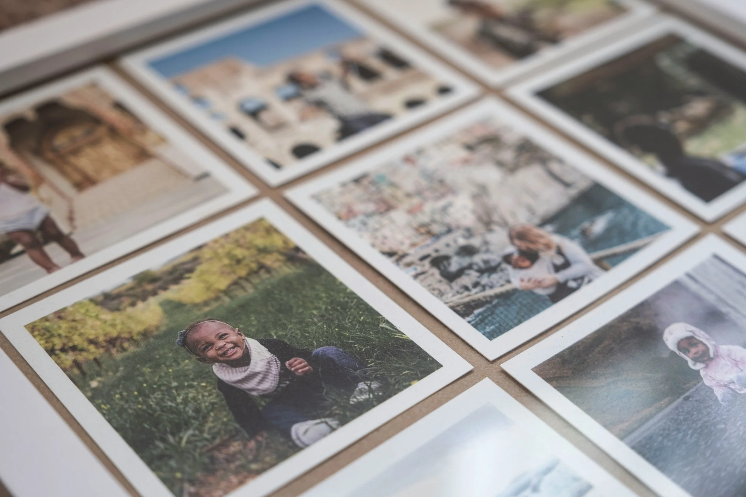 A collection of printed photographs laid out on a flat surface, showing various people and outdoor scenes.
