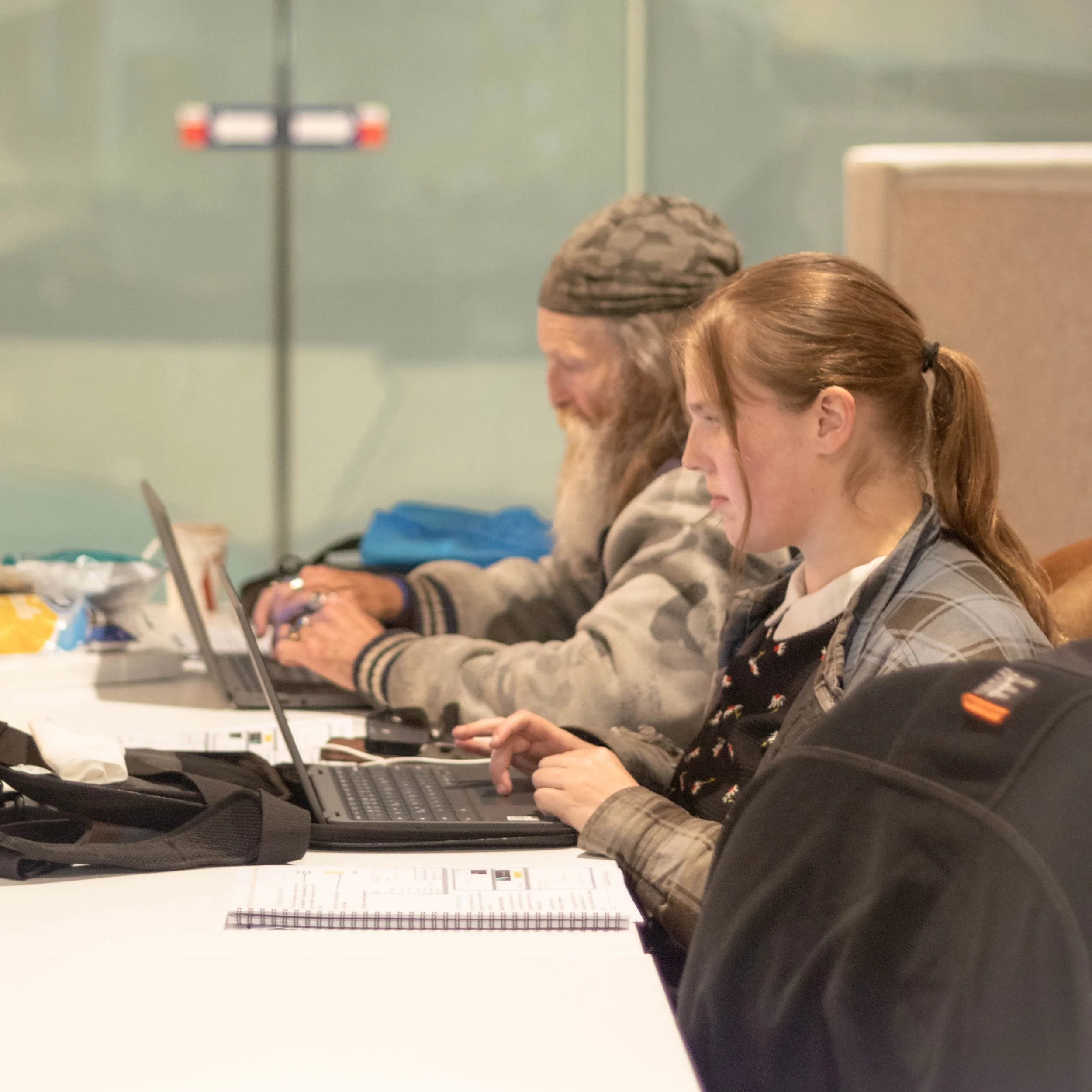 Katoa Connect learners working side by side on laptops during a digital skills training session, building confidence and practical technology skills in a supportive learning environment.