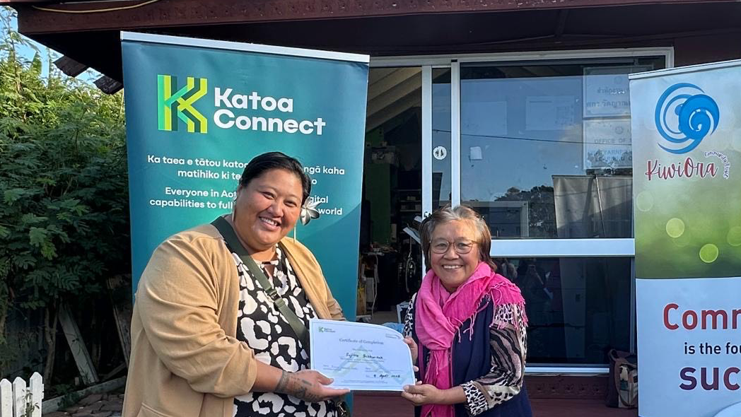 Katoa Connect facilitator presenting a certificate to a programme graduate outside a community venue, celebrating digital learning achievements and community partnership in Aotearoa New Zealand.