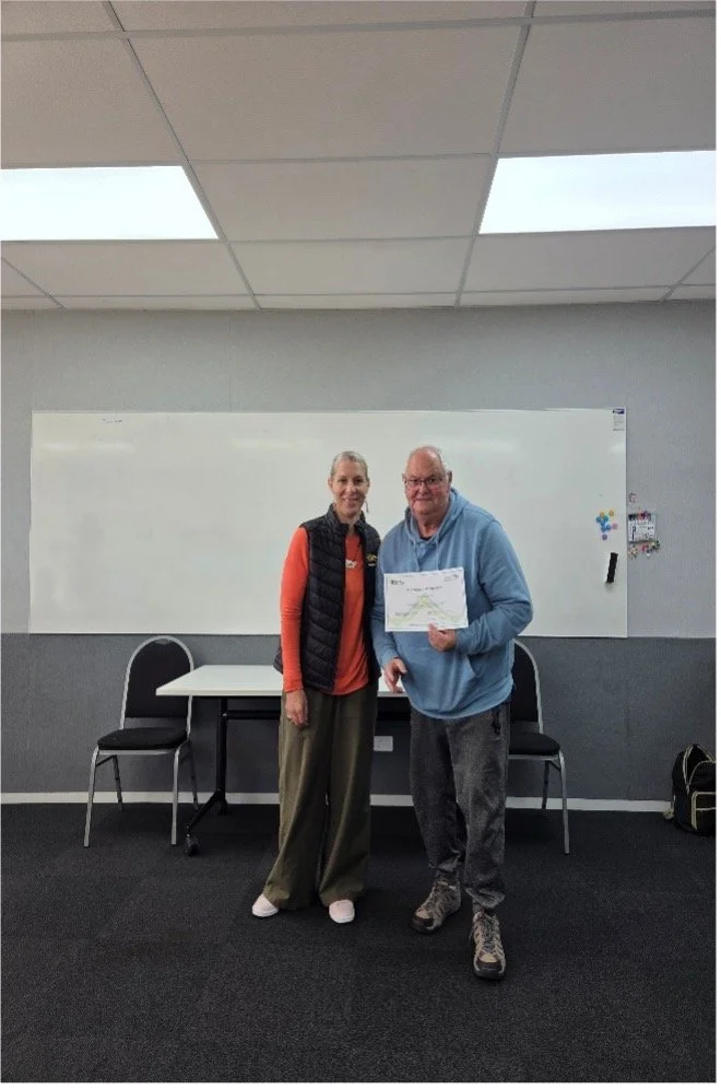 Success Stories: Michael standing proud with his certificate with CEO for Mai Lighthouse- Robyn Driver.