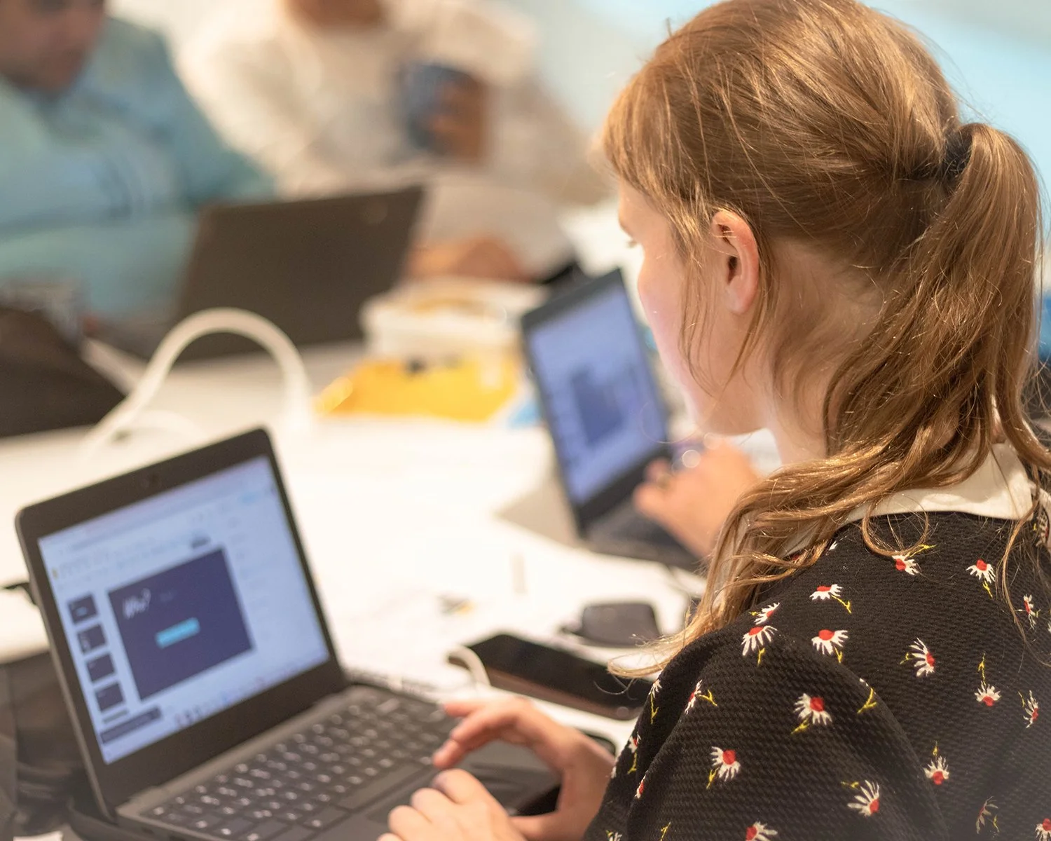 Young learner using a laptop during a Katoa Connect digital skills workshop, with other participants working in the background
