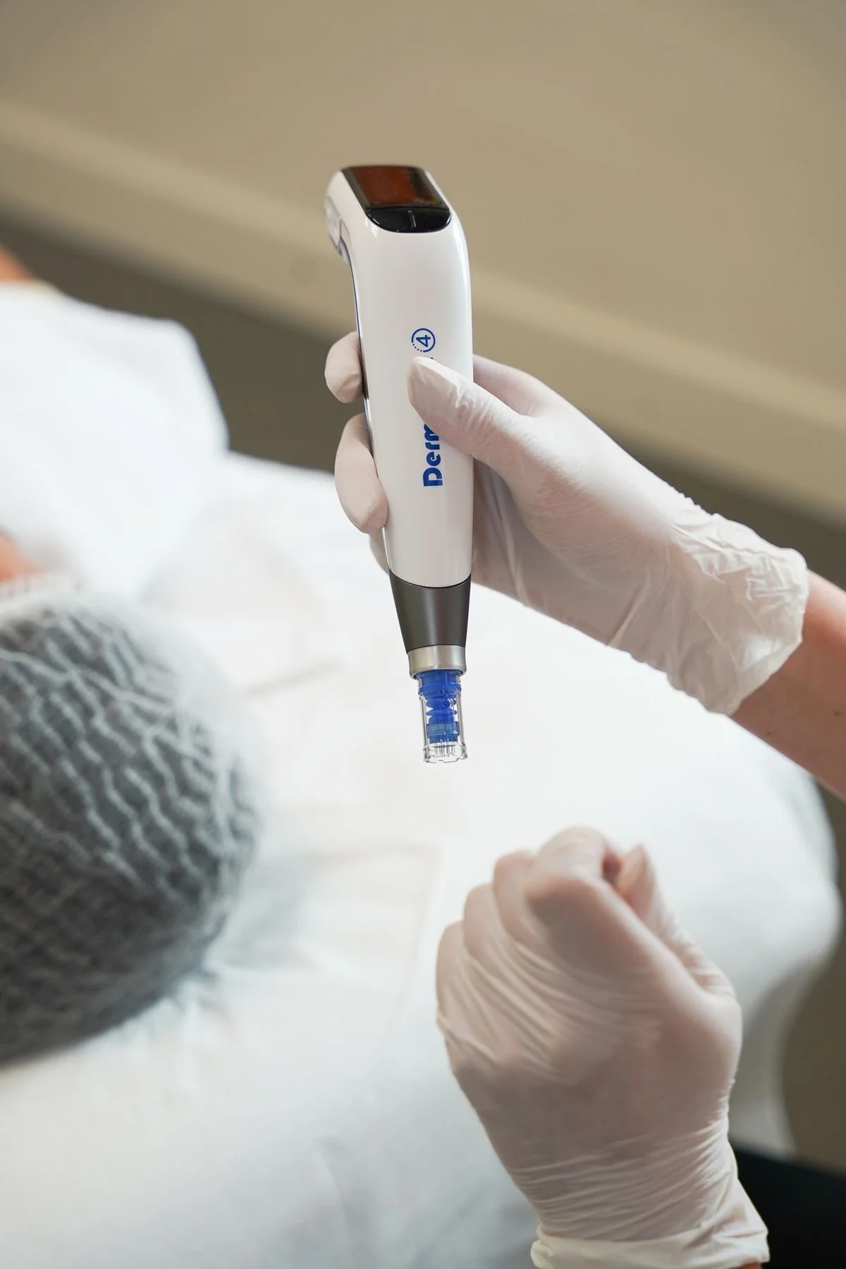 A healthcare professional in gloves holding a medical device, possibly performing a procedure on a patient.