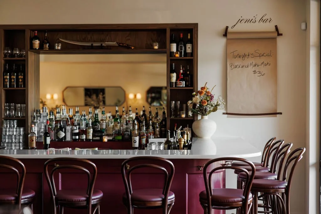 Hospitality design for a cozy neighborhood tavern featuring a beautiful mirror and liquor display, Farrow & Ball painted Bar, bentwood bar stools, specials board, floral display for a popular restaurant in Nashville, TN.