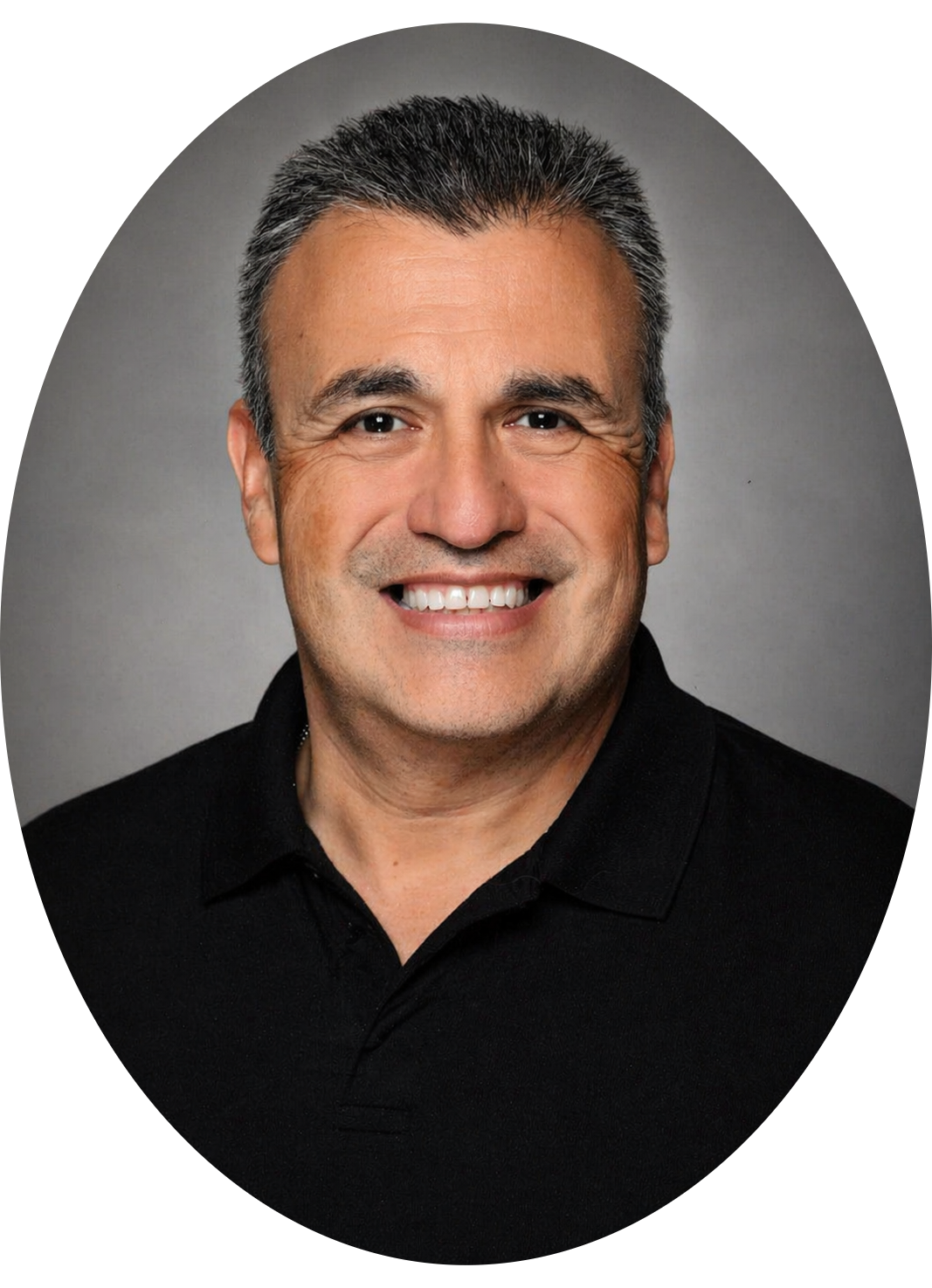 Smiling man with short dark hair wearing a black polo shirt, photographed against a gray background.