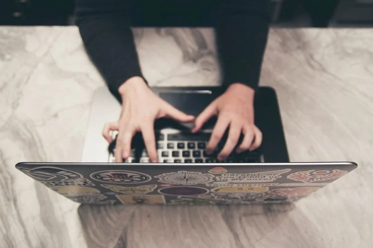 Overhead shot of a woman's hands typing on a silver laptop