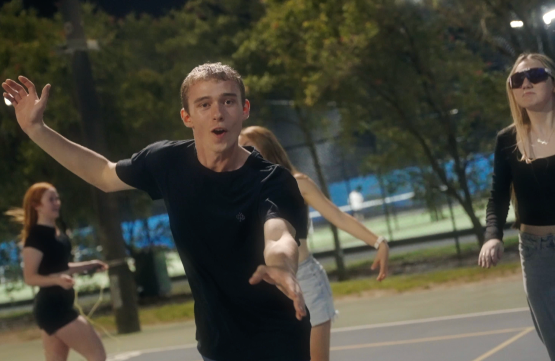 A group of young people dancing and enjoying themselves outdoors at night in a park.