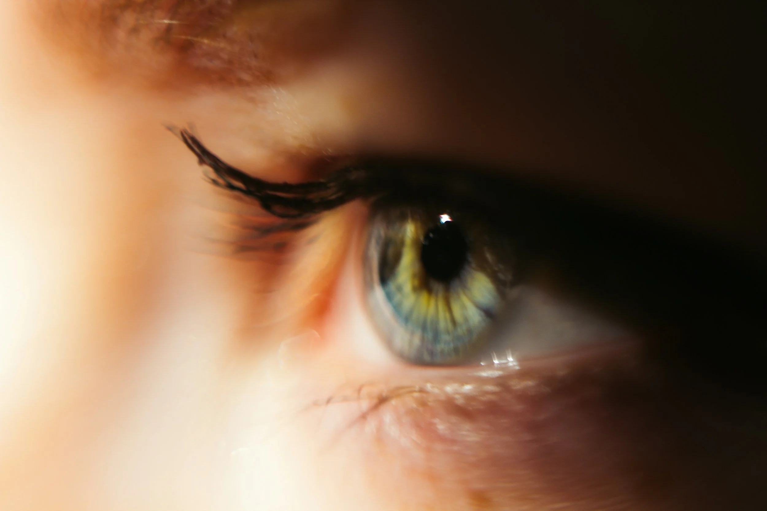 Close-up of a person's eye with detailed features including the iris, eyelashes, and surrounding skin.