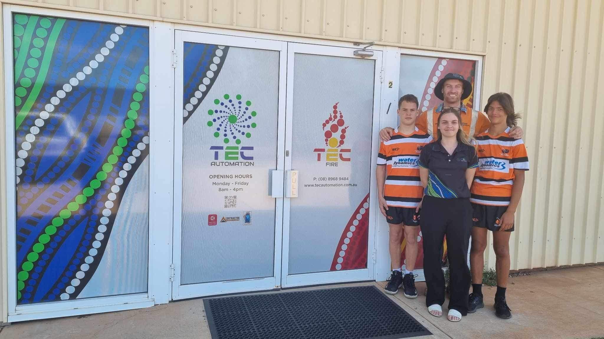 TEC Automation staff standing with three sponsored players.