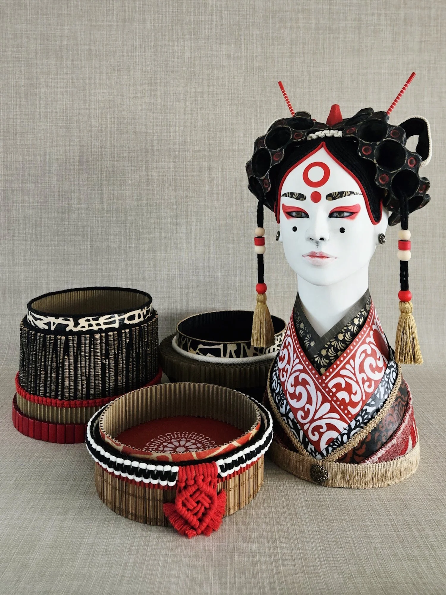 A display of traditional Asian baskets and a head sculpture with elaborate headdress and makeup.