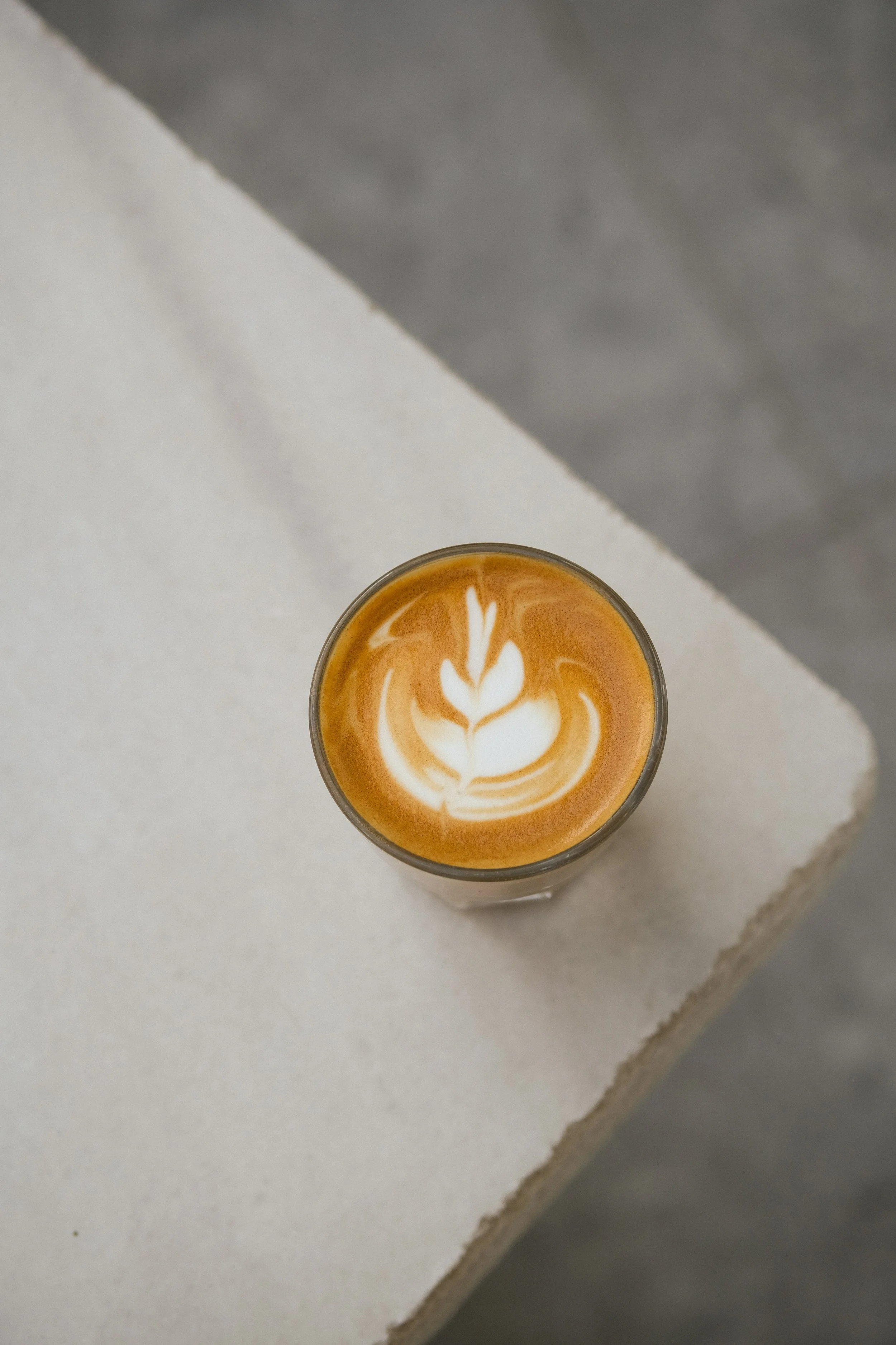 Latte art en forme de feuille dans une tasse en verre, café du brunch Héra Coffee Nice.