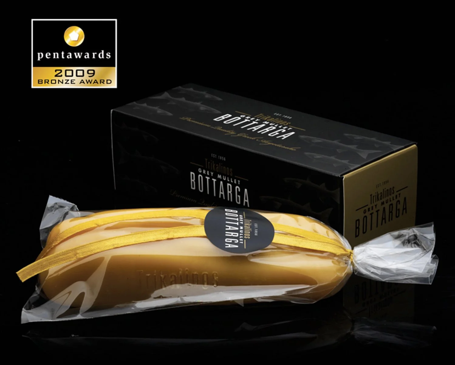 High-end commercial food photography for Trikalinos gray mullet bottarga product. Conceptual still life showing side by side product and packaging on black background. Part of a culinary strategy and brand asset project.