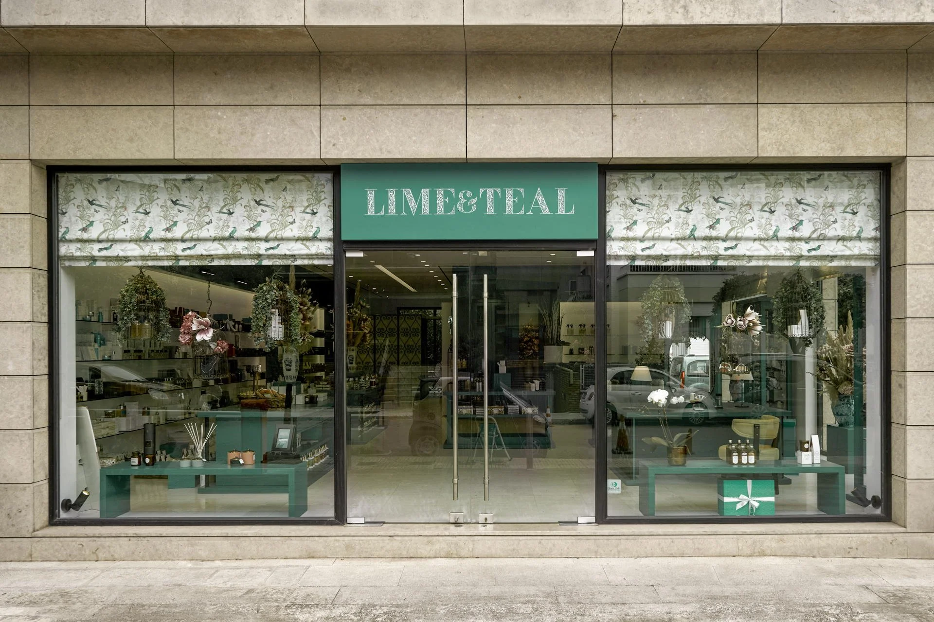 Main storefront facade of Lime & Teal perfume bar, showcasing architectural stone detailing and teal branding, photography by Stavros Kostakis Photography for Kyparissou Architects.