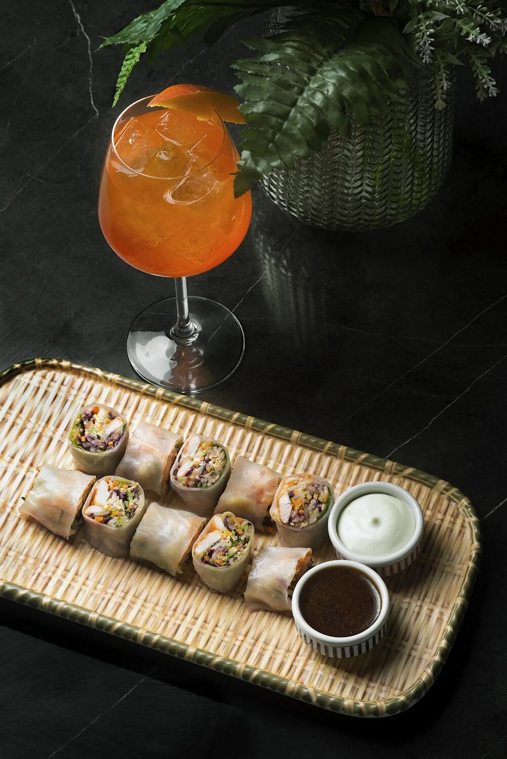 Asian fusion spring rolls on a bamboo platter paired with an orange cocktail at Royal Monkey Kifisia. Gastronomy photography by Stavros Kostakis Athens.