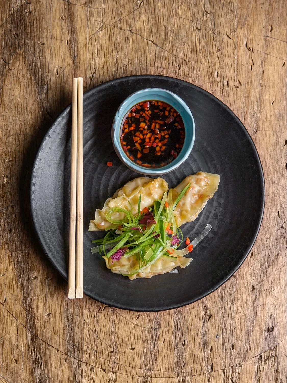Close-up flat lay of Asian fusion dumplings on a black plate, Jack Rabbit restaurant Utrecht, photographed by Stavros Kostakis.