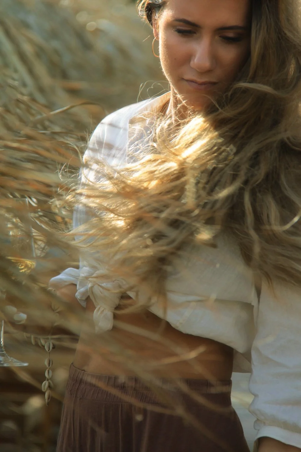 High-end hospitality concept photography: Atmospheric, sun-kissed lifestyle portrait at Bianco Beach House Tinos, emphasizing organic textures and the natural movement of wind-blown hair, captured in a cinematic documentary style by Stavros Kostakis