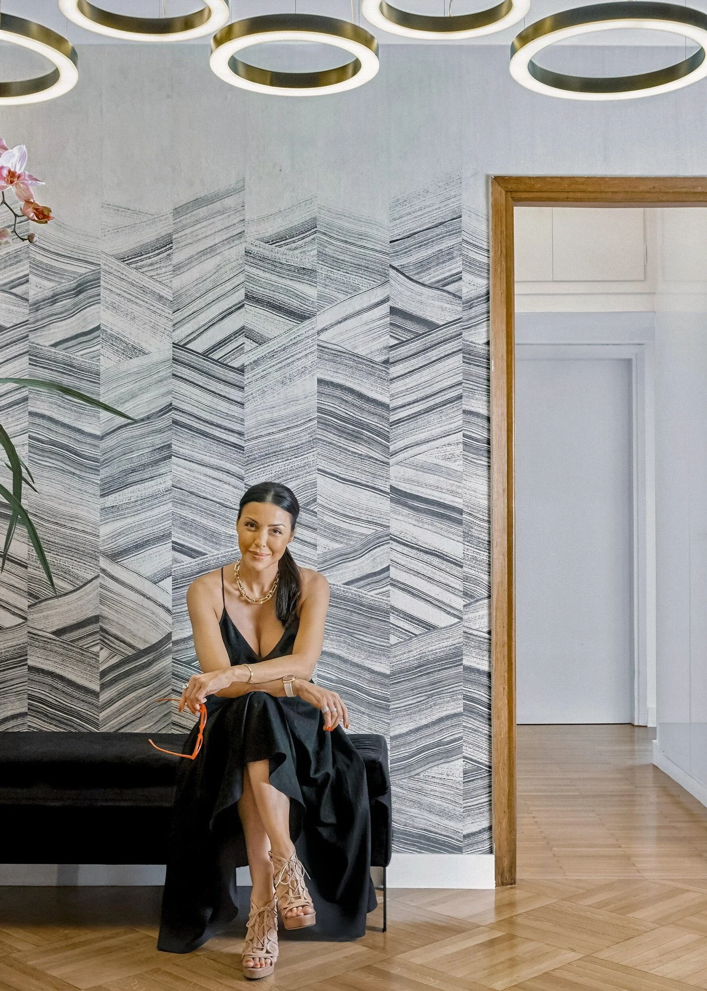 Elegant environmental portrait of interior designer Sissy Feida in a modern, luxury interior setting. The image showcases a sophisticated blend of architectural design and personal branding photography by Stavros Kostakis, featuring contemporary wall