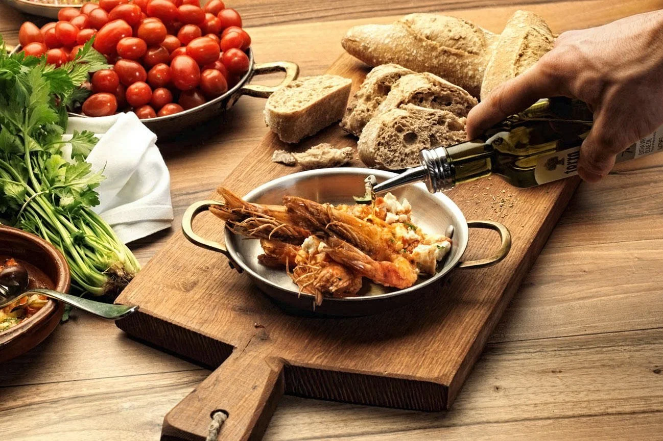 A snapshot of the living dining experience. Capturing the golden hour of a meal where fresh ingredients meet the ritual of service. Part of the culinary storytelling collection by Stavros Kostakis, emphasizing the warmth and authenticity of the Medit
