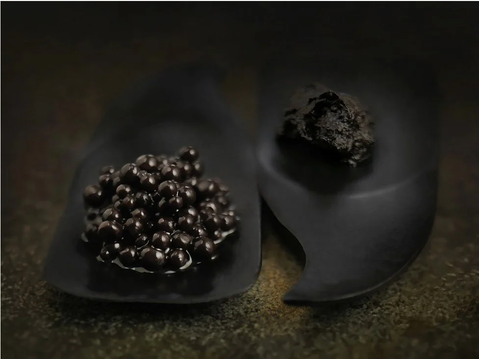 Commercial still life of Down Village Black Garlic on black ceramic spoons. Creative food photography by Stavros Kostakis.