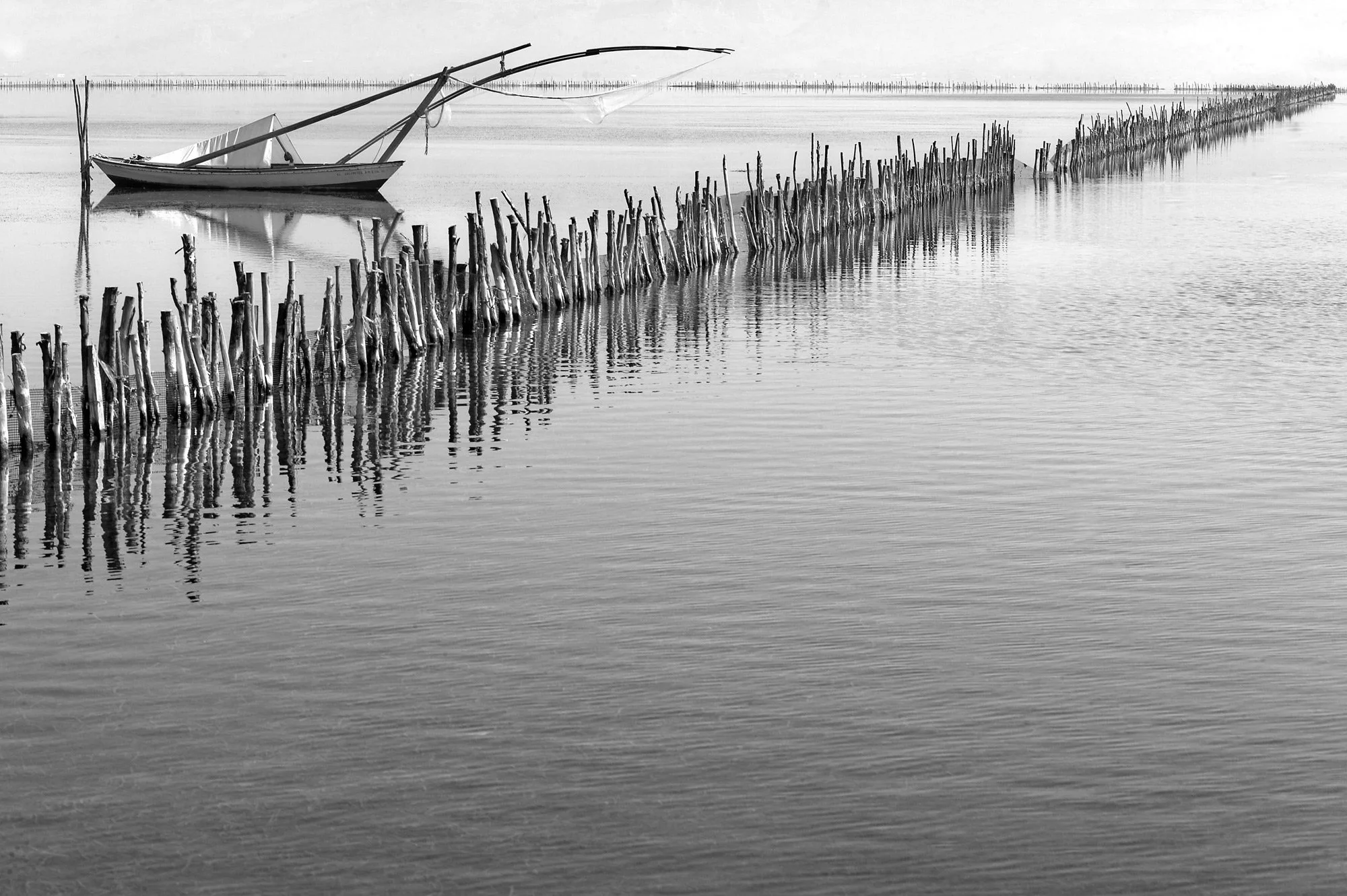 Traditional wooden Gaita boat near divaria fish traps, fine art landscape of Etoliko lagoon by Stavros Kostakis Photography.