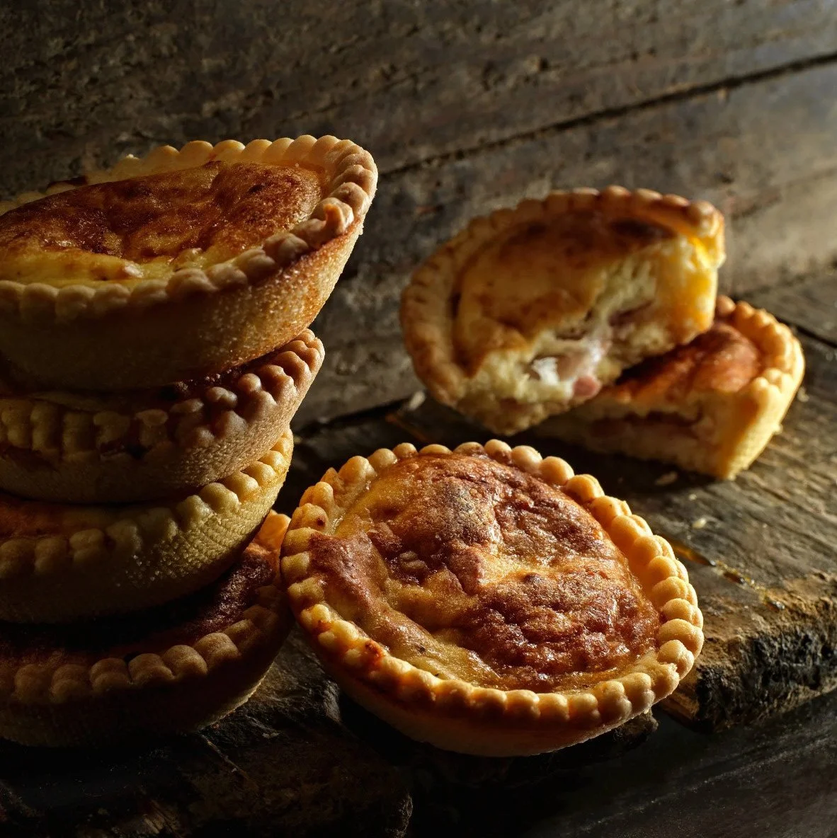 Professional food styling and photography of artisanal savory tarts on a rustic wooden surface for Argiro Barbarigou, by Stavros Kostakis.