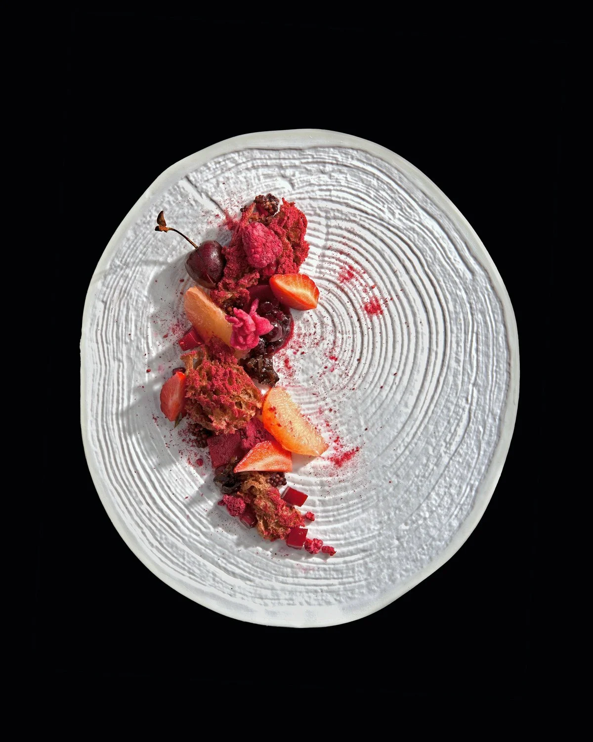 Visual Narrative Specialist & International Commercial Photographer on bespoke creative assignments Ozura Santorini  photographed a fine dining dessert, berry artisan plate ,top lay shot on black backround