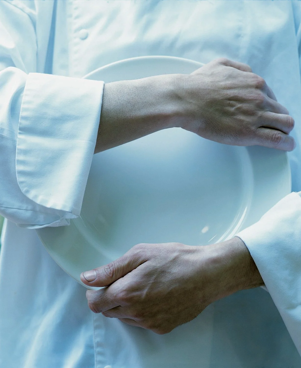 Conceptual hospitality photography by Stavros Kostakis featuring a chef holding a white plate, symbolizing the precision and art of the high-end dining experience.