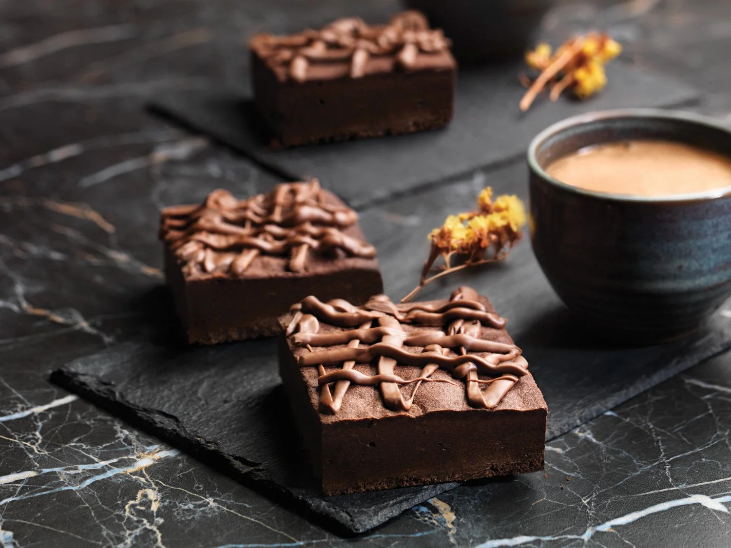 Professional moody food photography of gourmet chocolate brownies on black slate and marble surfaces, captured by Stavros Kostakis.
