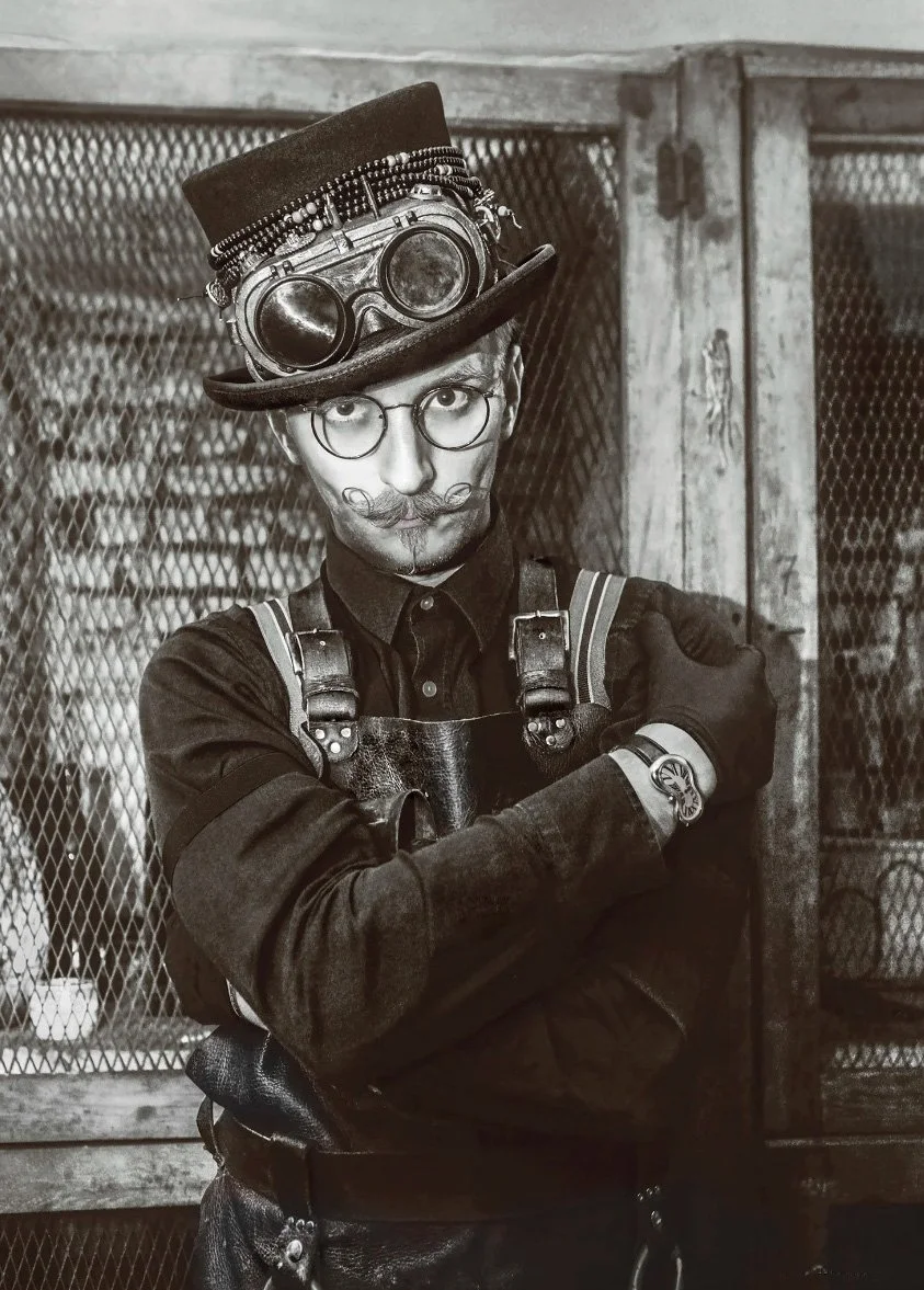 Portraits Archives Geremy Hussa Mixologist & Cladestino | A conceptual fine art portrait in Steampunk aesthetic. Mixologist Geremy Hussa is captured in black and white, featuring iconic elements like a vintage top hat, brass goggles, and a leather ap