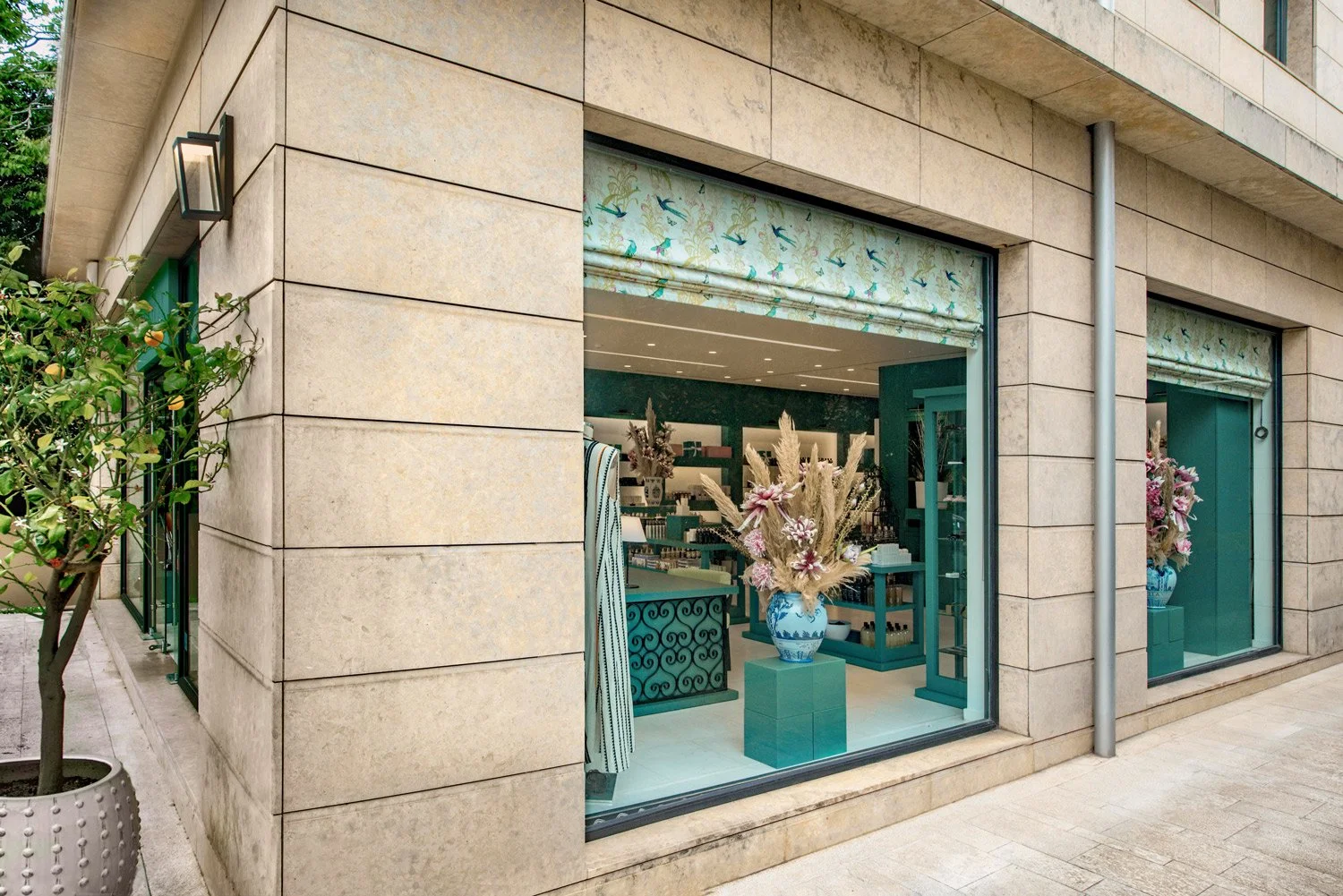 Detail shot of the store exterior featuring teal window frames and stone facade by Stavros Kostakis Photography.