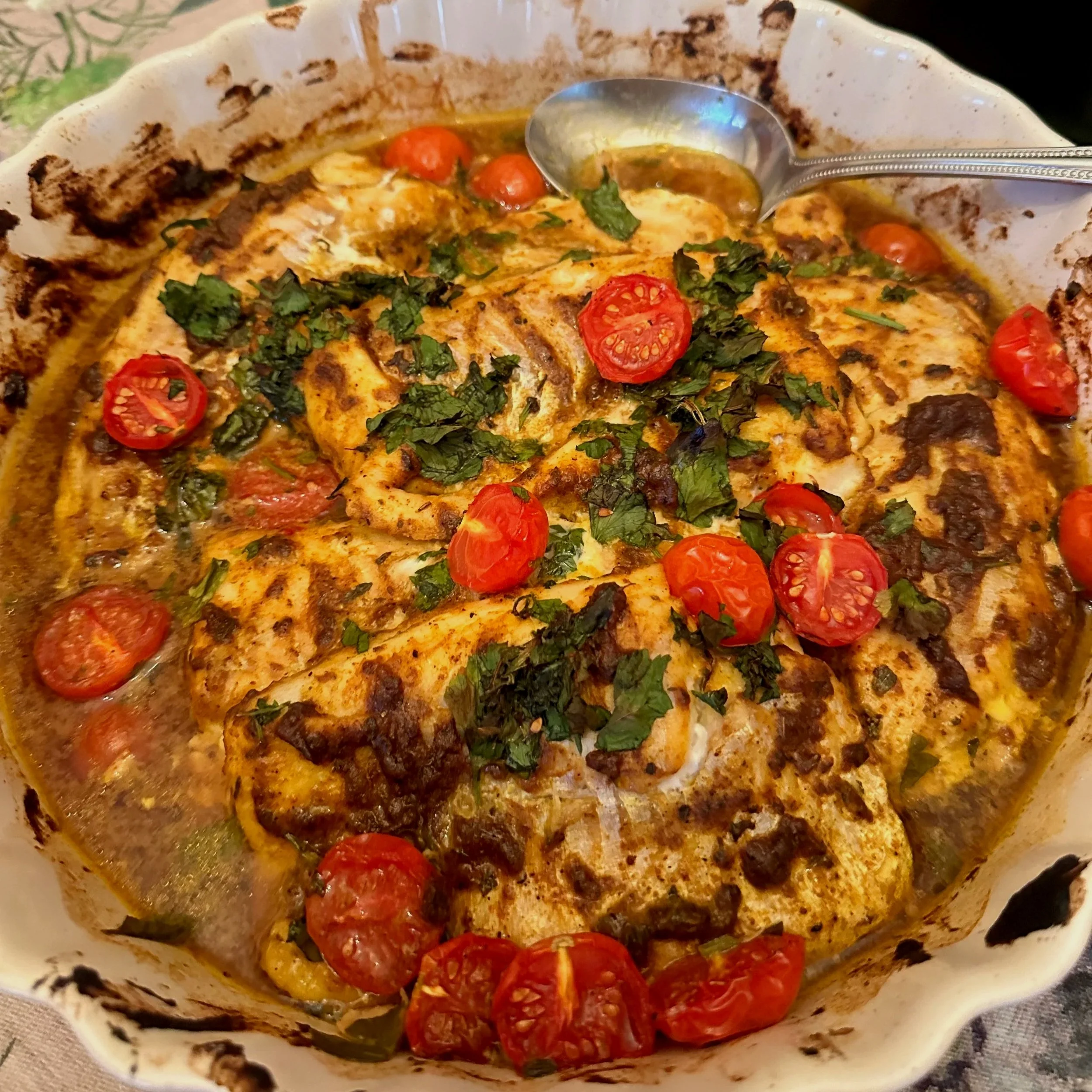 A close-up view of a bowl of food with grilled fish, white rice, and various vegetables in a wooden bowl.