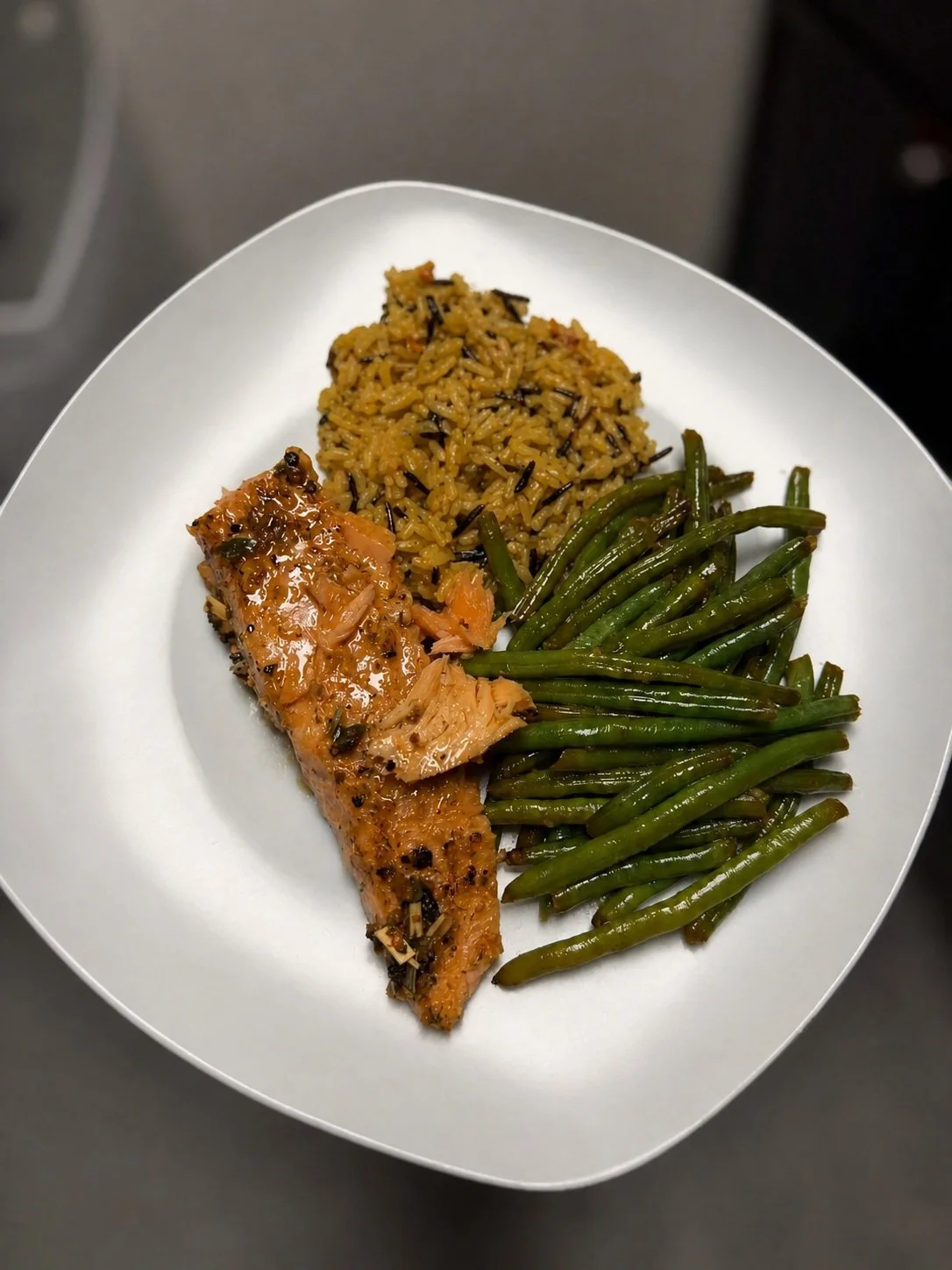 Plate with cooked salmon, rice with wild rice, and green beans