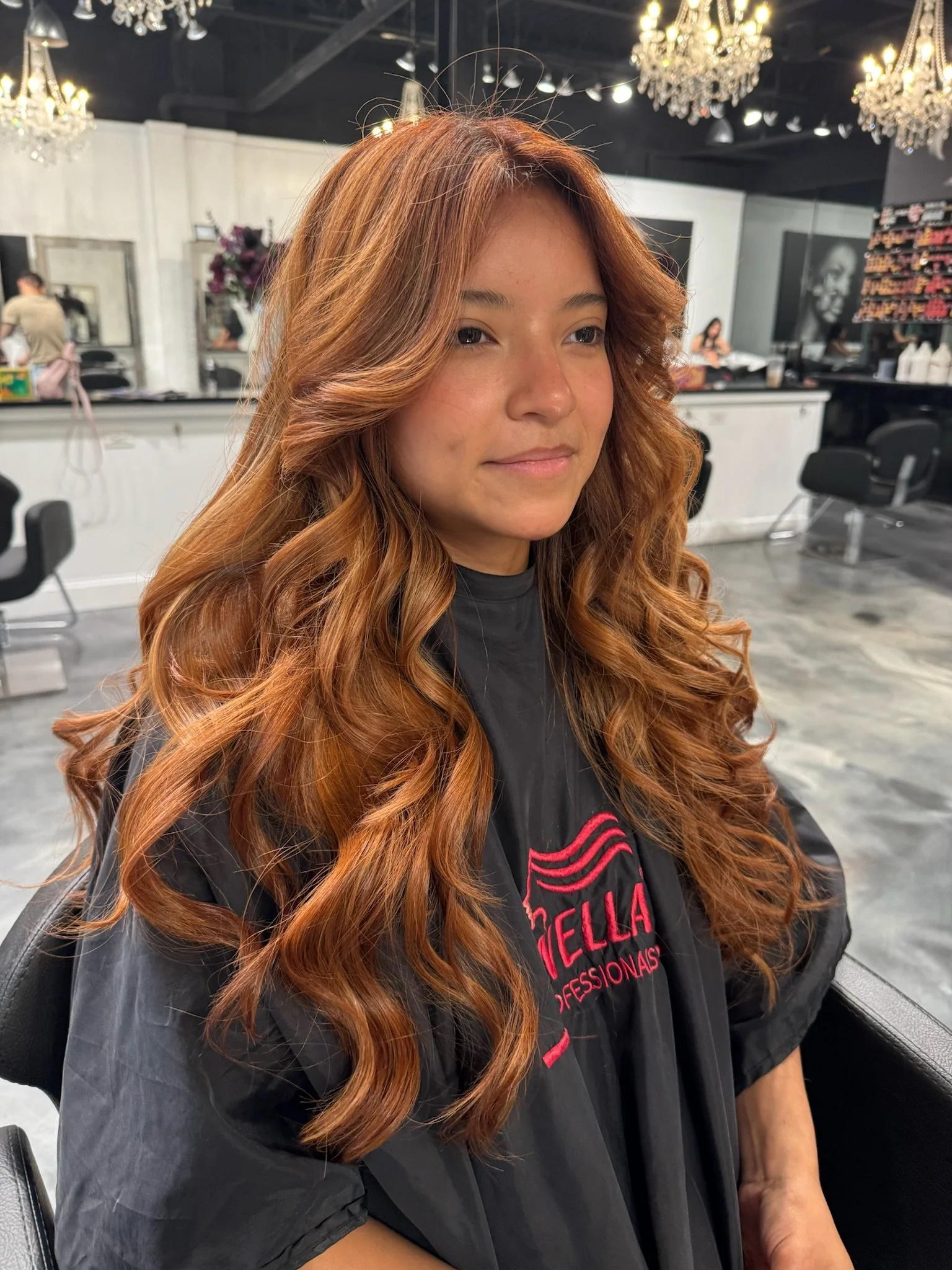 A woman with long, wavy, red hair in a salon.