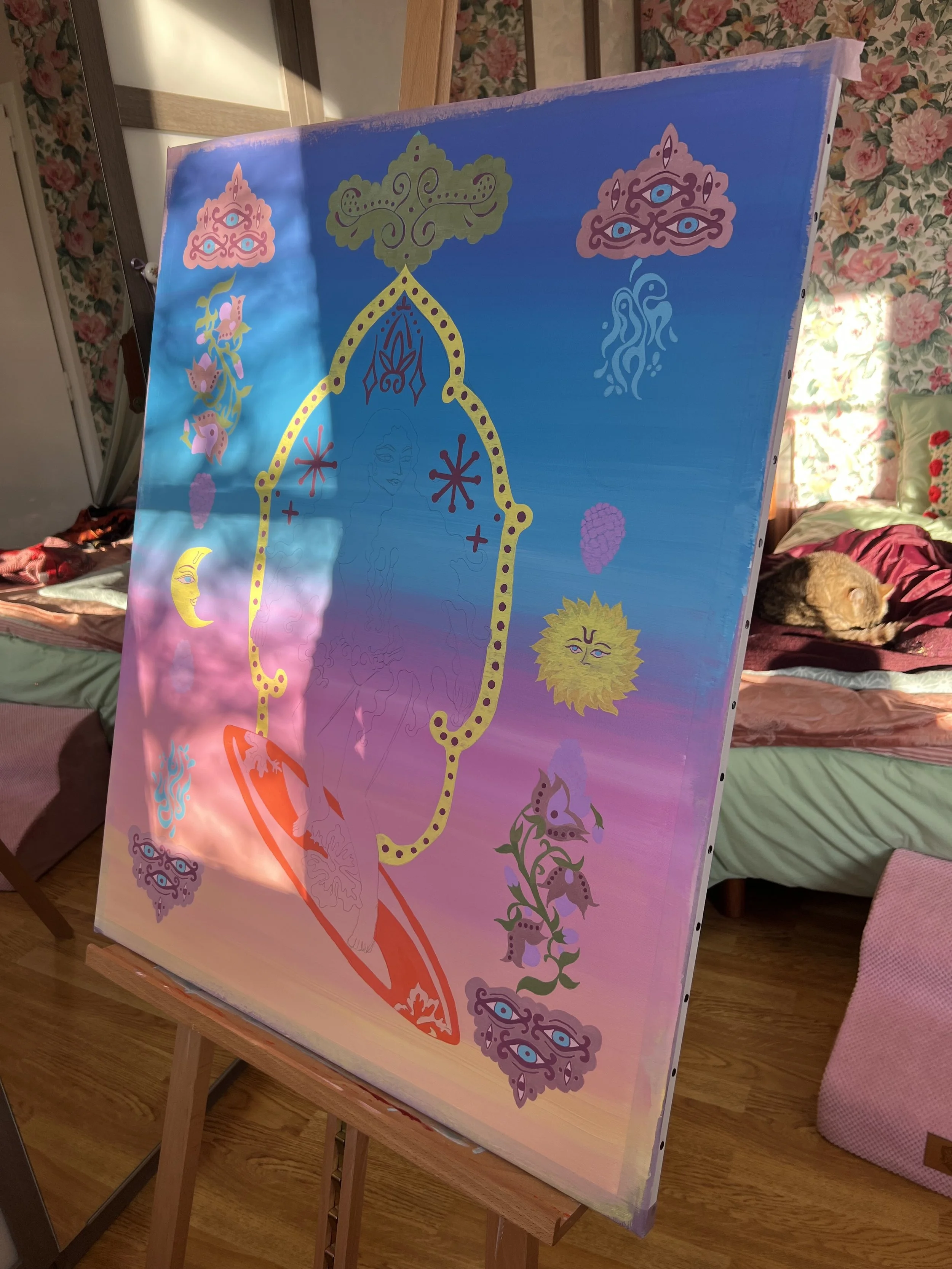Colorful abstract mural painting on canvas with various eyes, faces, flowers, and elements in vibrant pastel shades, mounted on an easel in a cozy room with floral wallpaper, a cat resting on a bed, and furniture visible in the background.