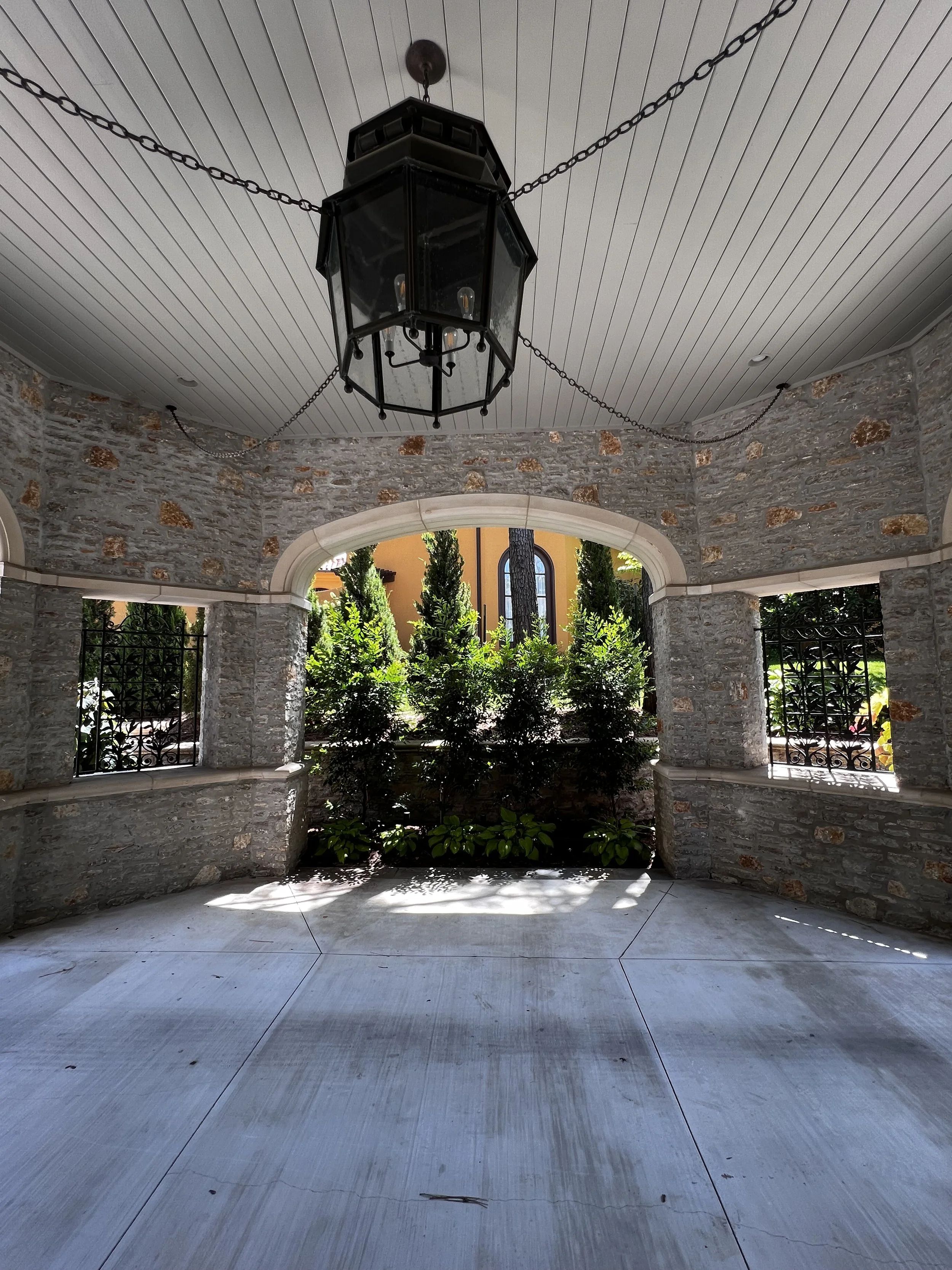 Custom outdoor living space in Tulsa with patio seating, outdoor kitchen, fireplace, pergola, and landscape lighting