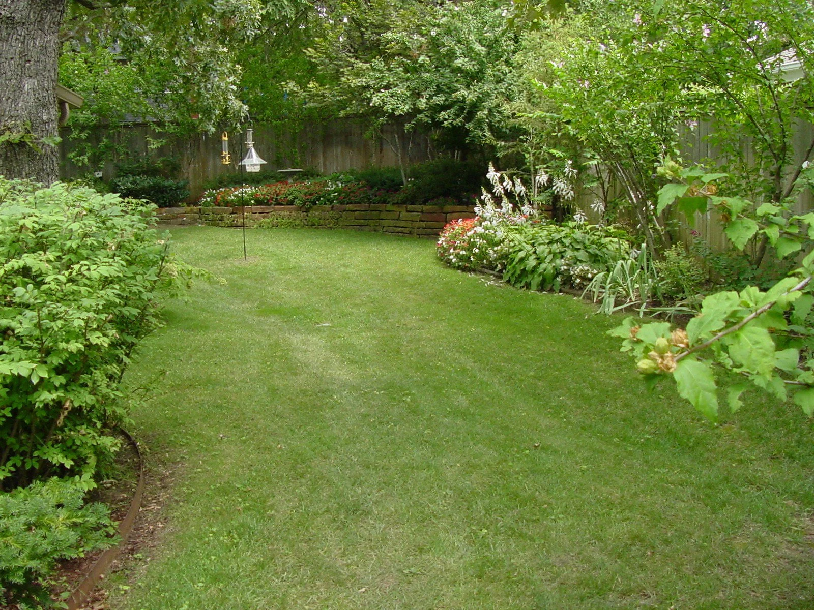 Backyard landscaping project in Tulsa with garden beds, stone patio, and lighting