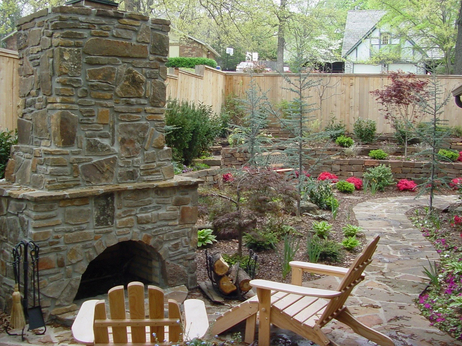 Custom outdoor living space in Tulsa with patio seating, outdoor kitchen, fireplace, pergola, and landscape lighting