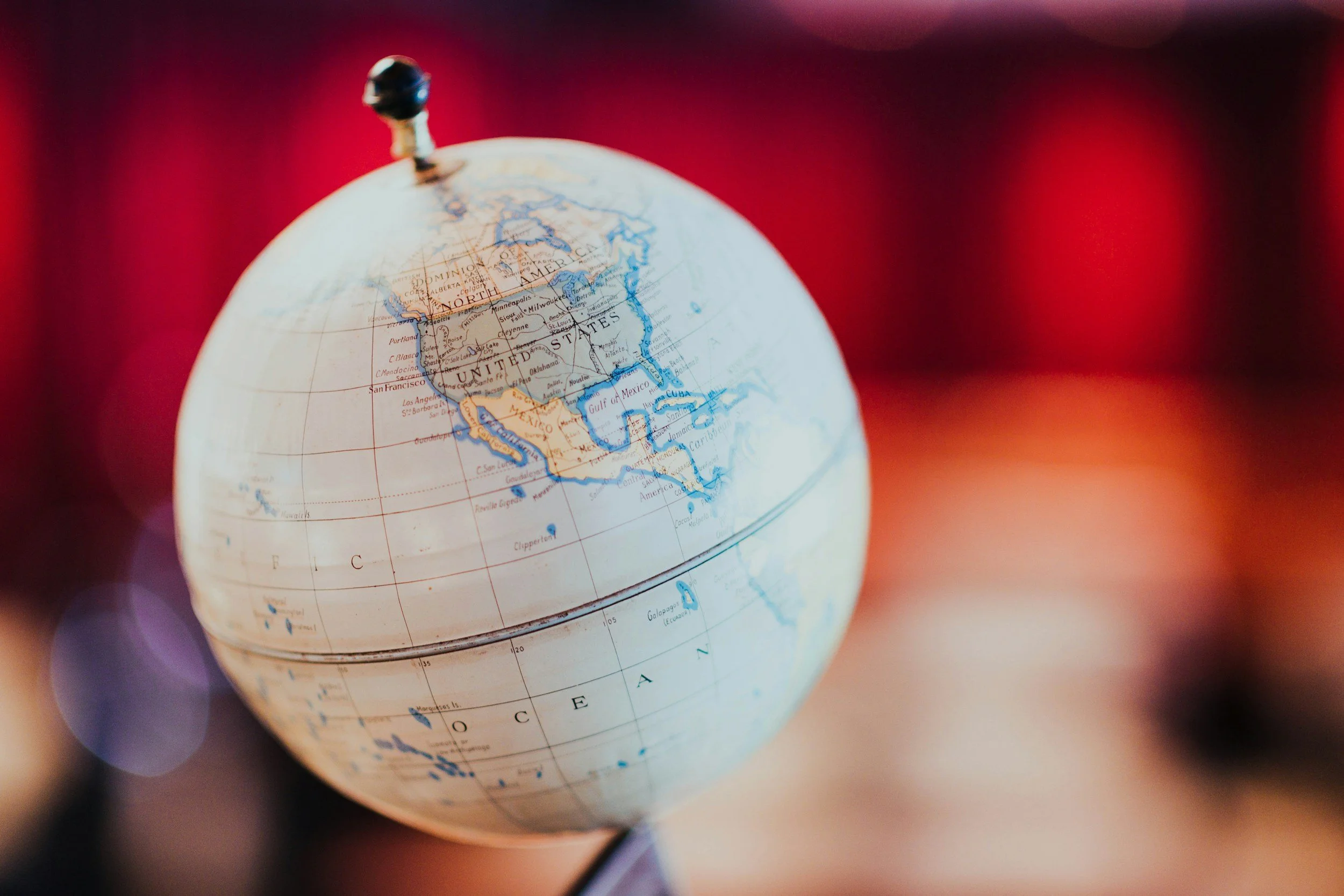 A globe centered on North America and the Atlantic Ocean with a reflective surface and blurred colorful background.