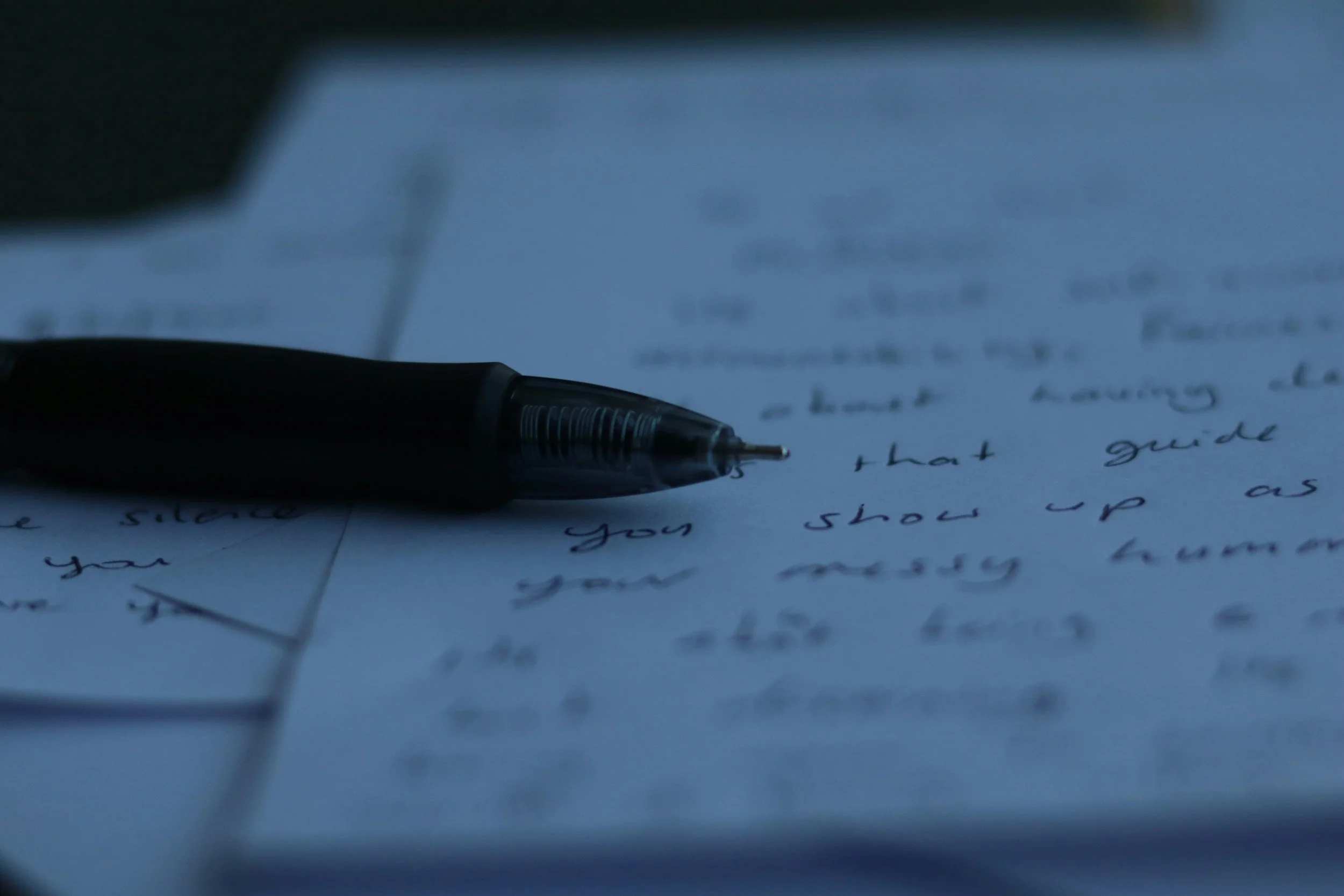 Close-up of a ballpoint pen resting on handwritten notes on paper.
