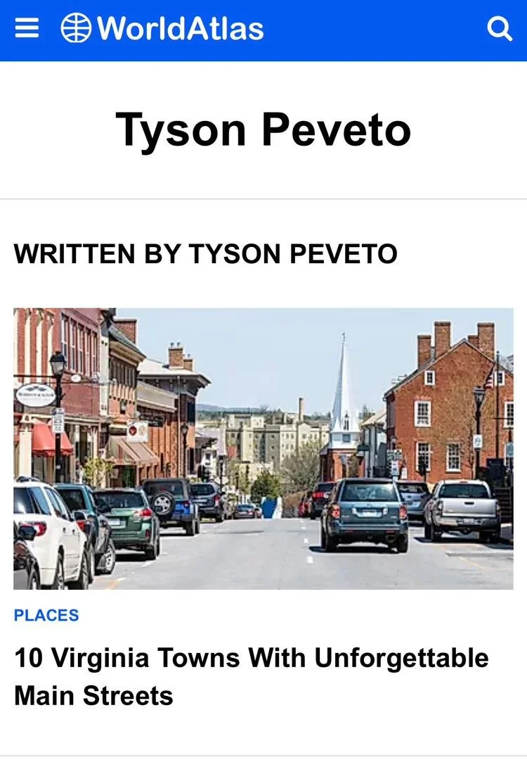 Tyson Peveto's author page on World Atlas, showing an article's main image featuring a street view of a small town with parked cars and brick buildings, featuring a church with a steeple in the background.