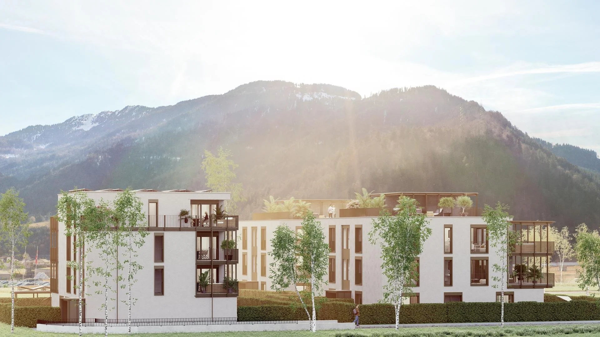 Moderne weiße Wohngebäude mit mehreren Etagen und Terrassen, umgeben von Bäumen, vor einer Bergkulisse.
Überbauung Ginellas an bester Lage in Bonaduz in den Bündner Bergen in der Schweiz. Wohneigentum der gehobenen Klasse.