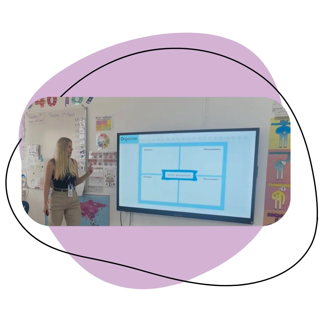 A teacher standing in front of a large digital screen in a classroom, presenting a slide about 'Organise' with sections including definition, characteristics, examples, and non-examples, with colorful educational wall decorations in the background.