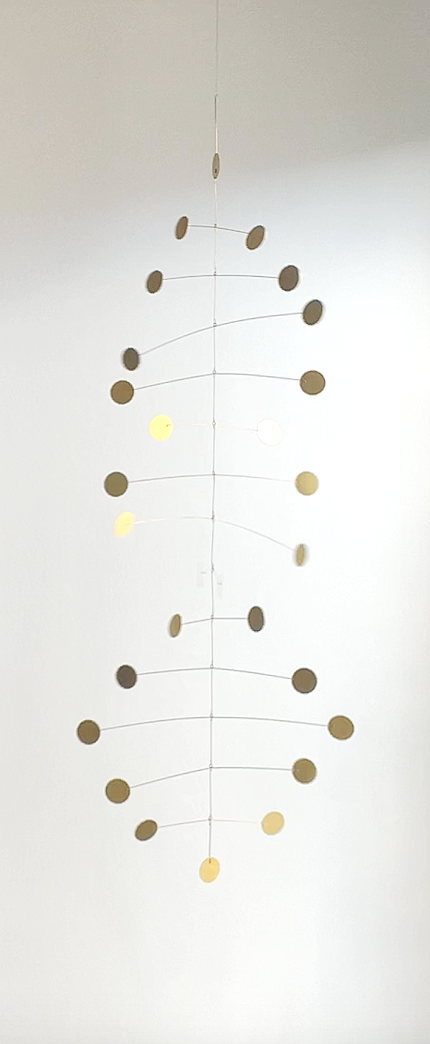 Mobile suspendue en forme d'ADN avec des cercles de différentes couleurs, blanc et beige.