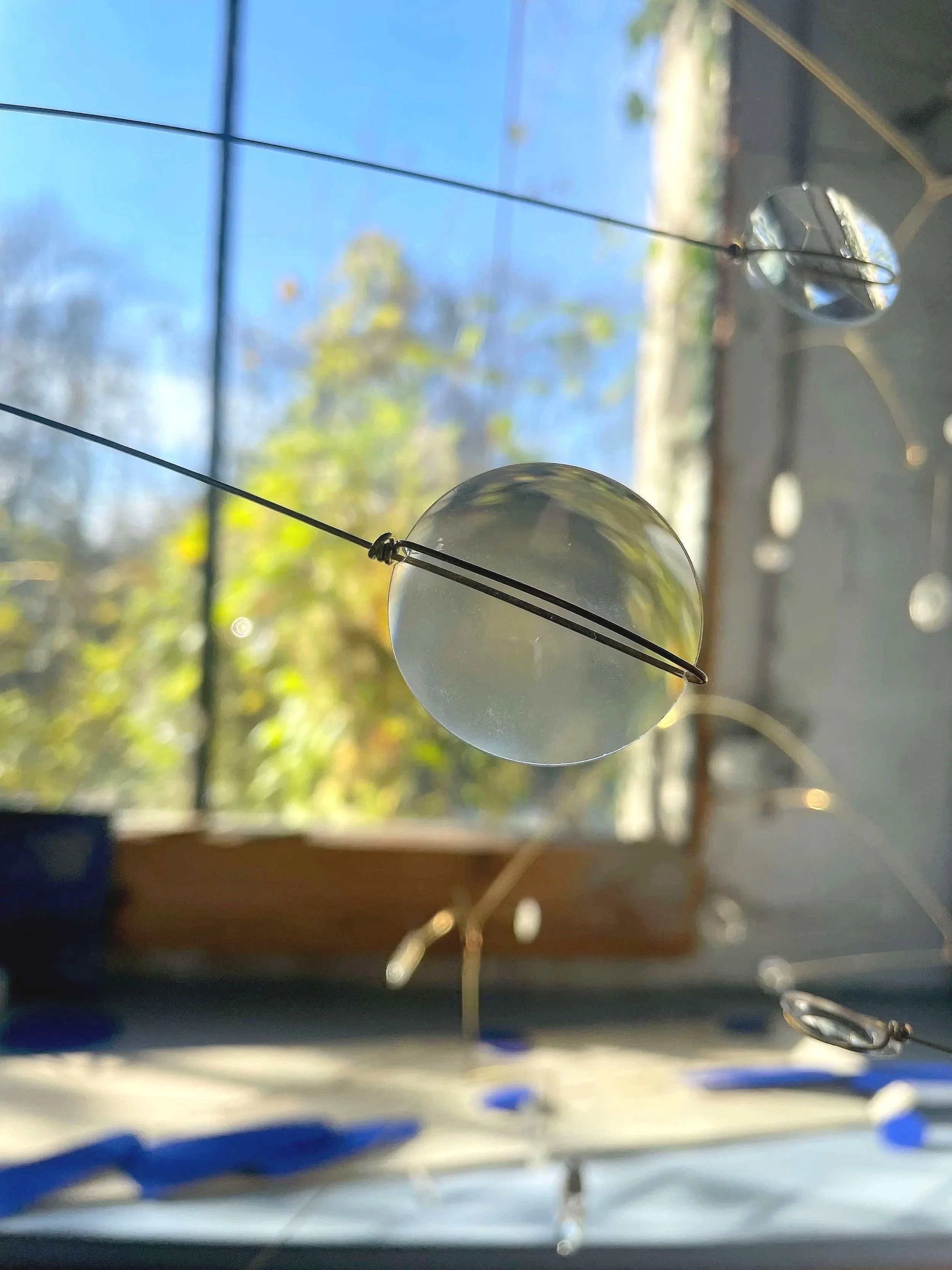 Une décoration de vitrine avec des ballons transparents et des fils suspendus, regardant à travers une fenêtre avec un paysage en arrière-plan.