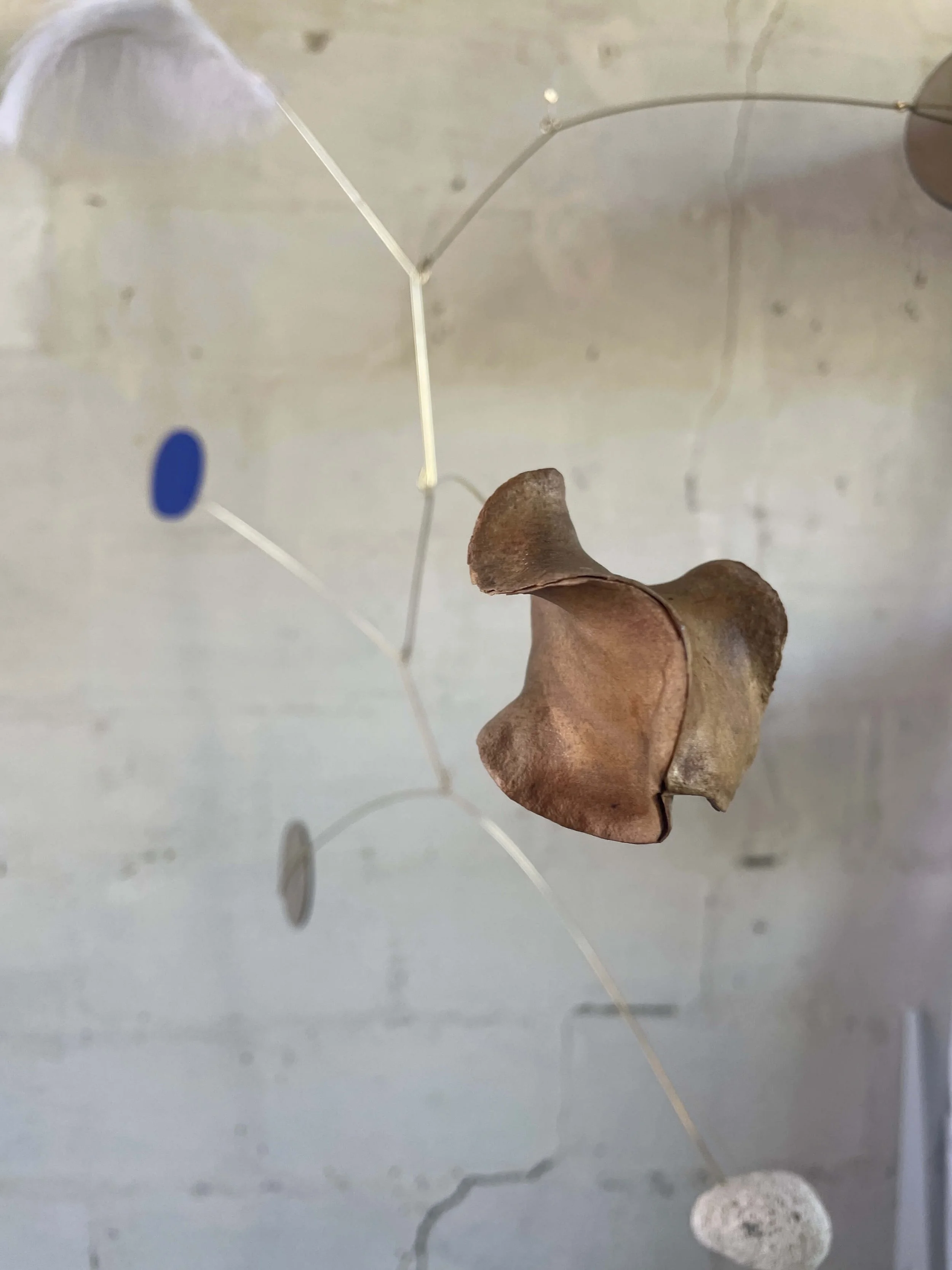 Une structure métallique avec une pièce en bois ou en quelque chose de semblable suspendue en son centre, avec un fond grisâtre.