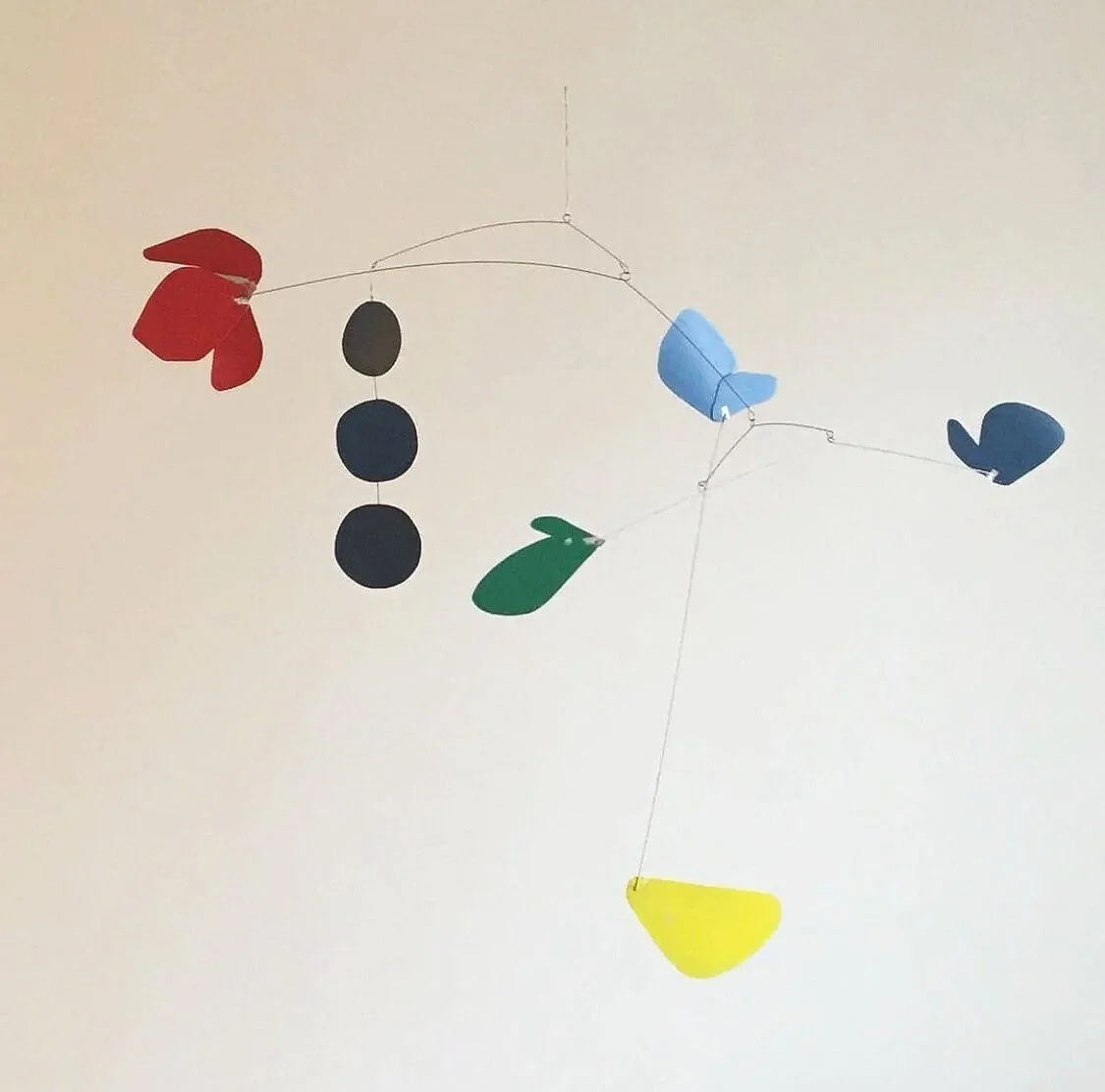 Mobile suspendu avec des formes colorées en forme de fleurs, de feuilles, de fruits et d'oiseaux, suspendues par des fils.